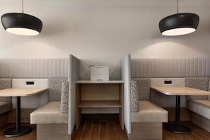 Interior moderno de restaurante con asientos tipo cabina, mesas e iluminación colgante.