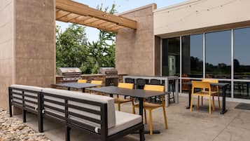 An outdoor patio with seating, tables, and a grill area.