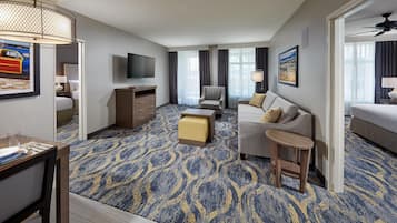 Habitación de hotel con cama, sofá, escritorio, televisor y alfombra estampada.