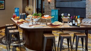 Una barra de buffet con diversos alimentos y una selección de botellas de vino.