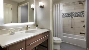 A bathroom with a large mirror, a sink, a toilet, and a shower area.