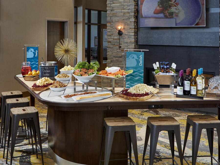 Bar de buffet con diversas opciones de comida, entre ellas ensaladas, salsas y una selección de vinos.