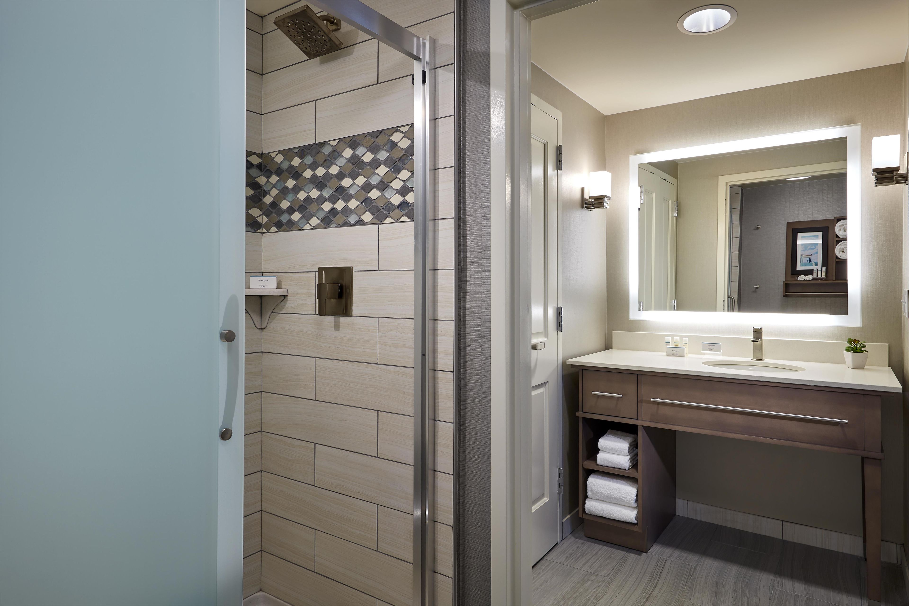 A modern bathroom with a shower, a vanity with a mirror, and a towel rack.