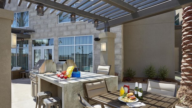 Un patio exterior con una parrilla, una mesa de comedor y sillas.