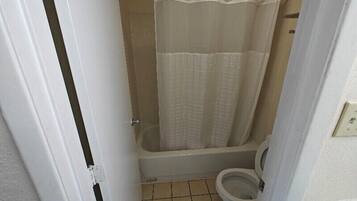 A small bathroom with a bathtub, toilet, and a shower curtain.