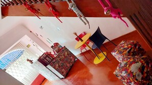 Une pièce avec un plafond en bois, un canapé à motifs, une petite table avec des chaises et un coussin coloré.