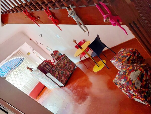 Una habitación con techo de madera, un sofá estampado, una pequeña mesa con sillas y un cojín colorido.