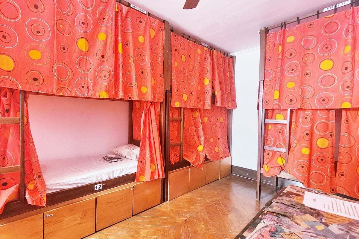 A room with bunk beds, wooden cabinets, and patterned curtains.