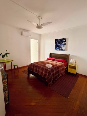 A bedroom with a bed, a nightstand, a ceiling fan, a door, and a small table with a plant. - Red Monkey Hostel: Barra Funda (São Paulo)
