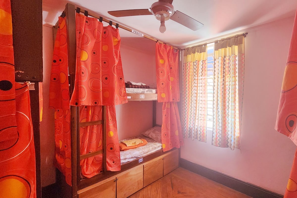 A room with bunk beds, a ceiling fan, and curtains with circular patterns.