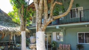 A building with a thatched roof, outdoor seating, and potted plants.