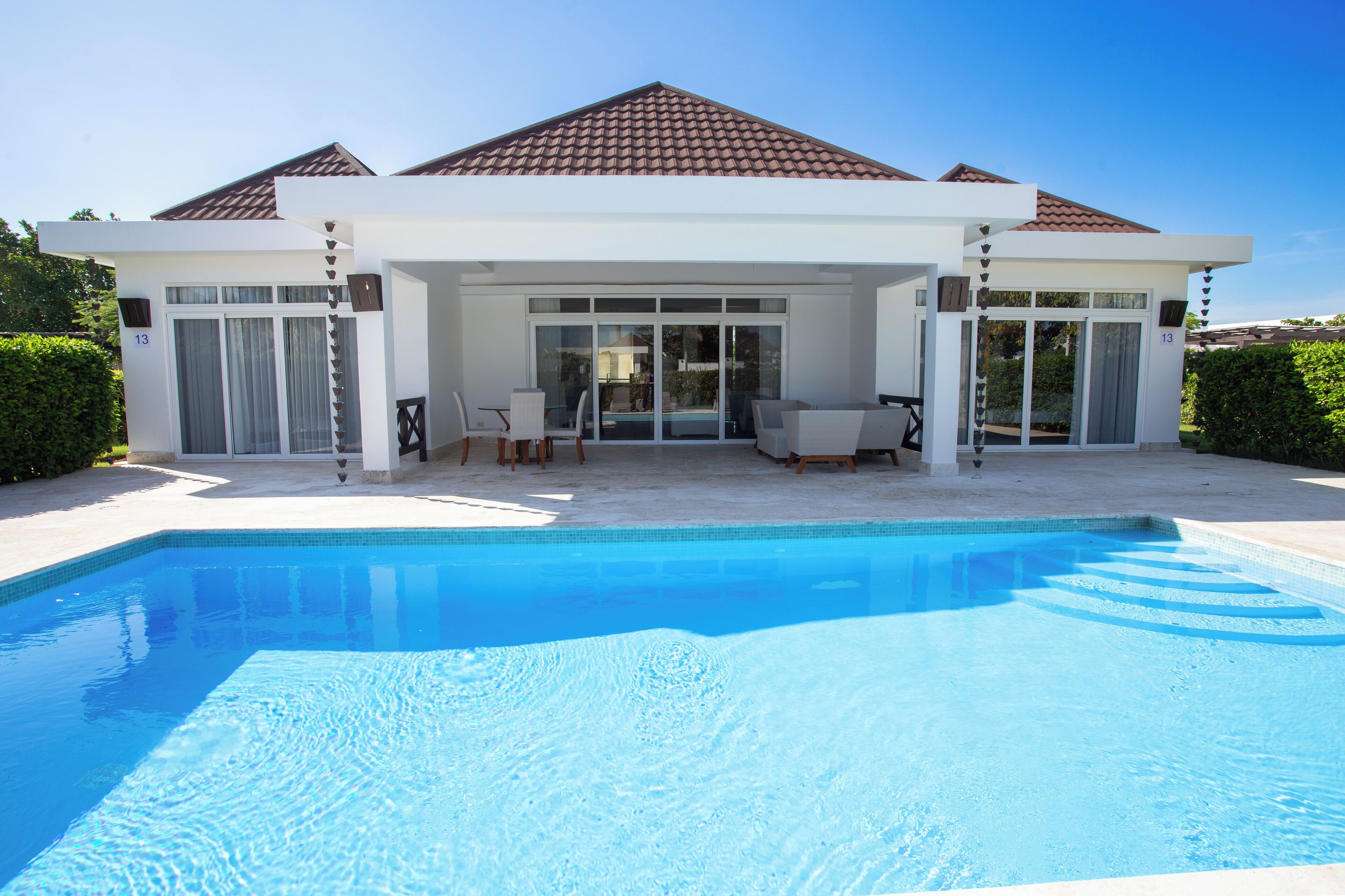 Una casa moderna con piscina, ampie vetrate e un patio.