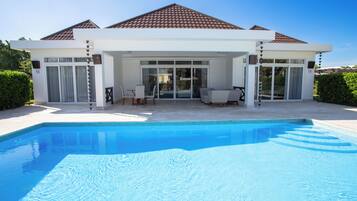 Una casa moderna con piscina, ampie vetrate e un patio.