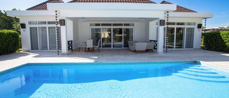 A modern house with a swimming pool, large glass doors, and a patio area.