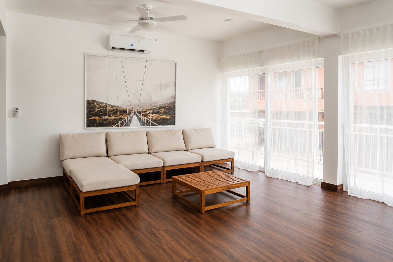 Uma sala de estar moderna com um sofá, uma mesa de centro de madeira e um ventilador de teto.