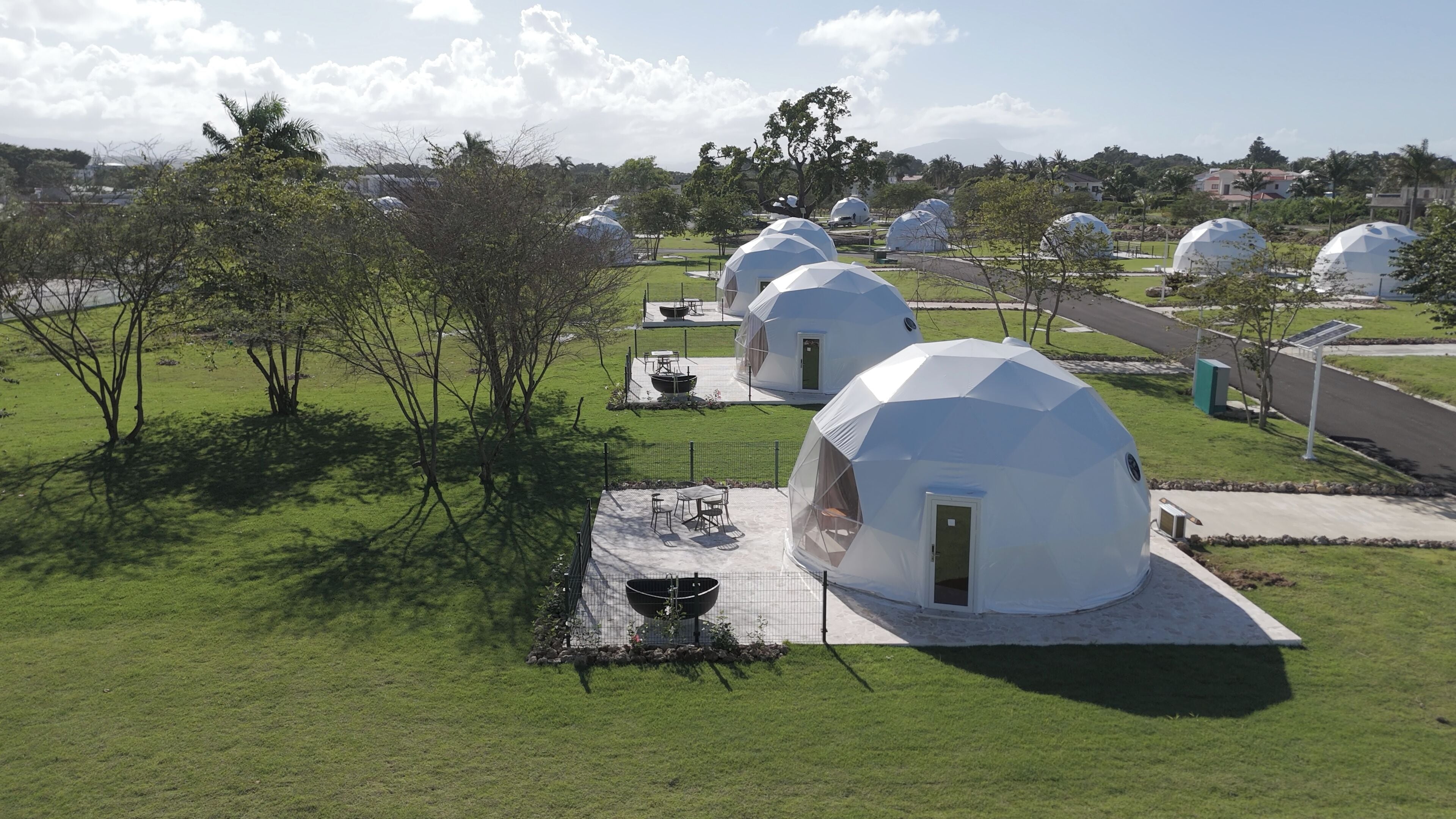 A series of geodesic dome structures with a flat roof, surrounded by a grassy area and trees.