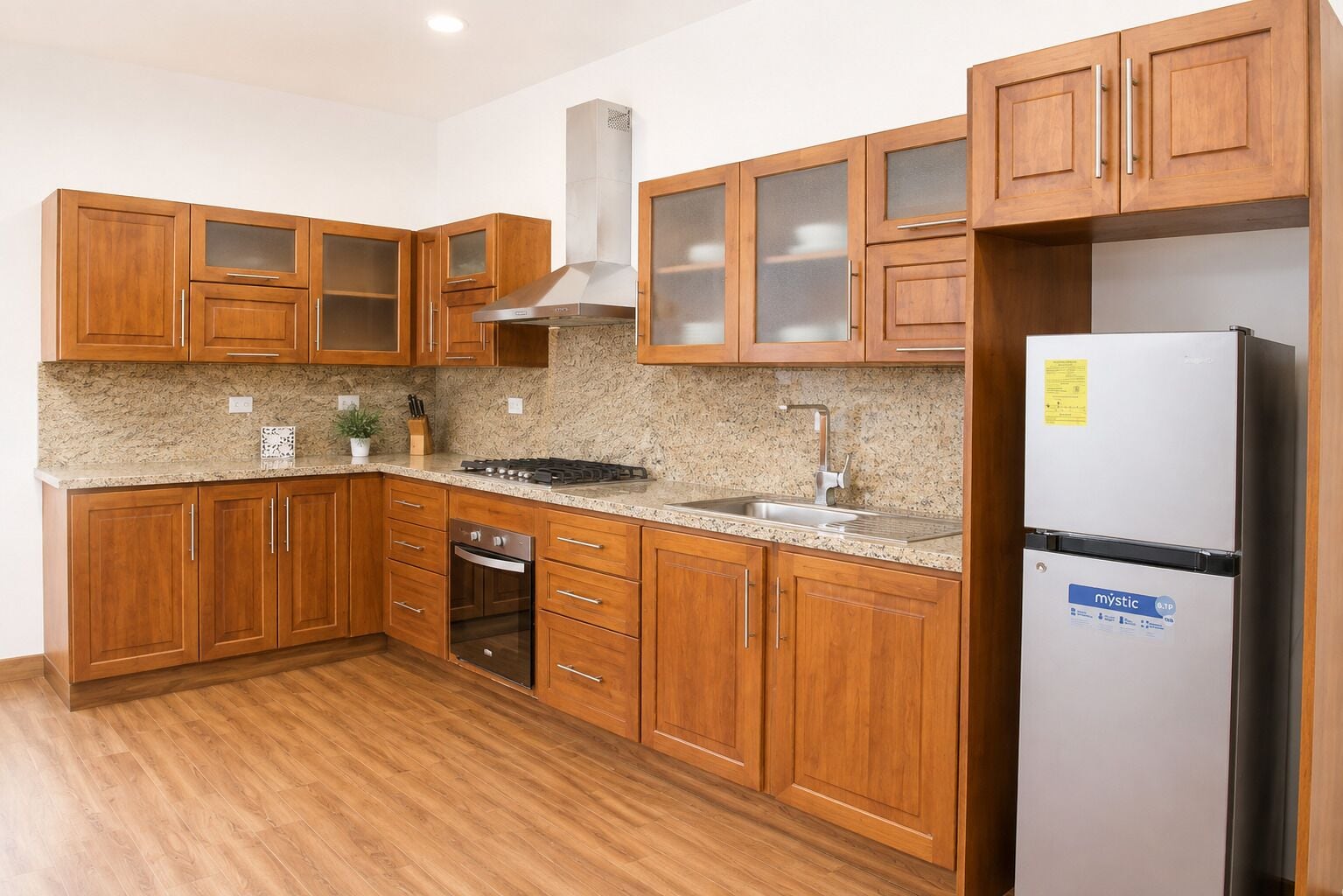 A kitchen with wooden cabinets, a stainless steel refrigerator, and a granite countertop.