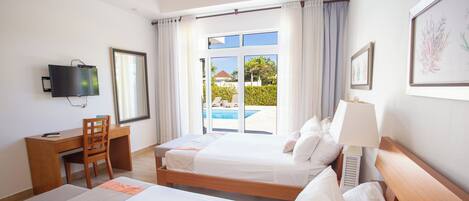 A hotel room with two beds, a desk, a chair, a TV, and a view of a swimming pool.