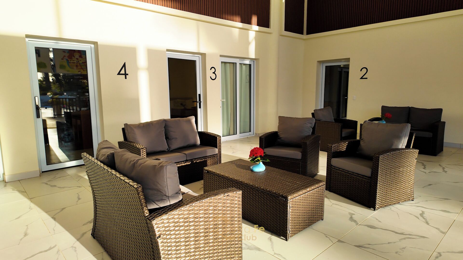 A spacious outdoor seating area with wicker furniture and a marble floor.