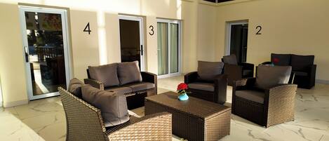 A spacious outdoor seating area with wicker furniture and a marble floor.