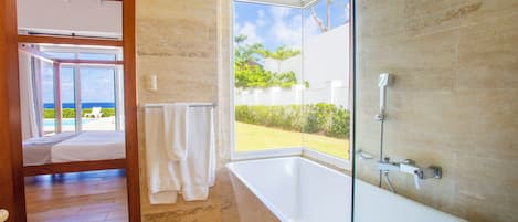 A modern bathroom with a bathtub, a shower, and a large window offering a view of the outdoors.