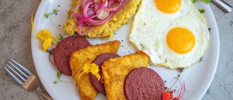 Un plato con huevos revueltos, huevos fritos y salchichas.