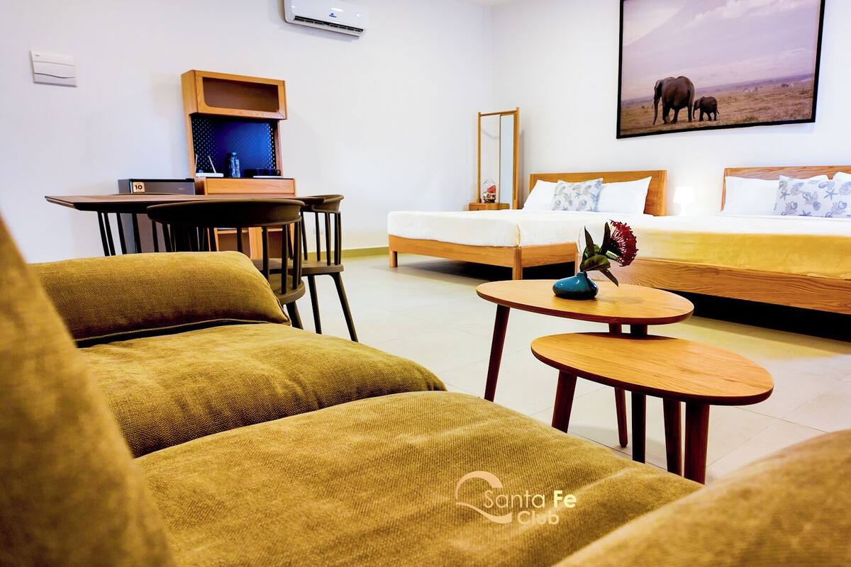 A hotel room with a bed, two chairs, a desk, and a small table.