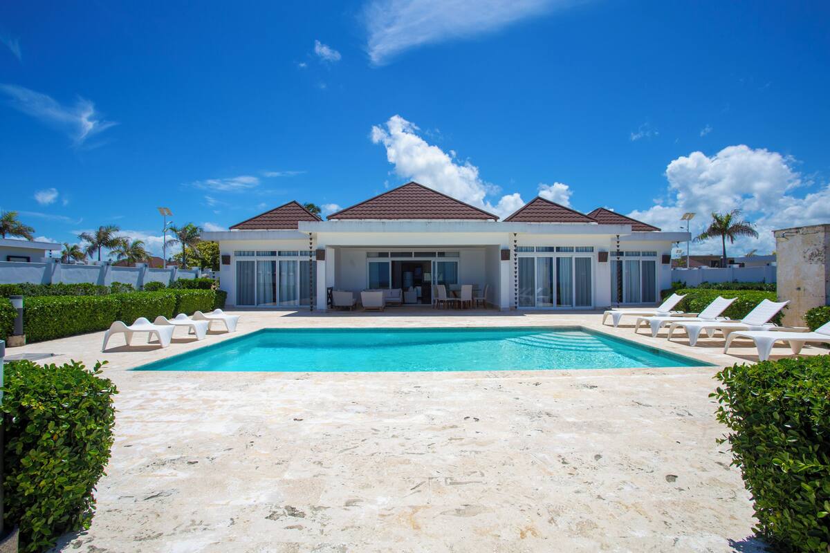 A resort with a swimming pool, lounge chairs, and a covered outdoor seating area.