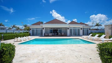 Un resort con piscina, sillas de descanso y un espacio de estar techado al aire libre.