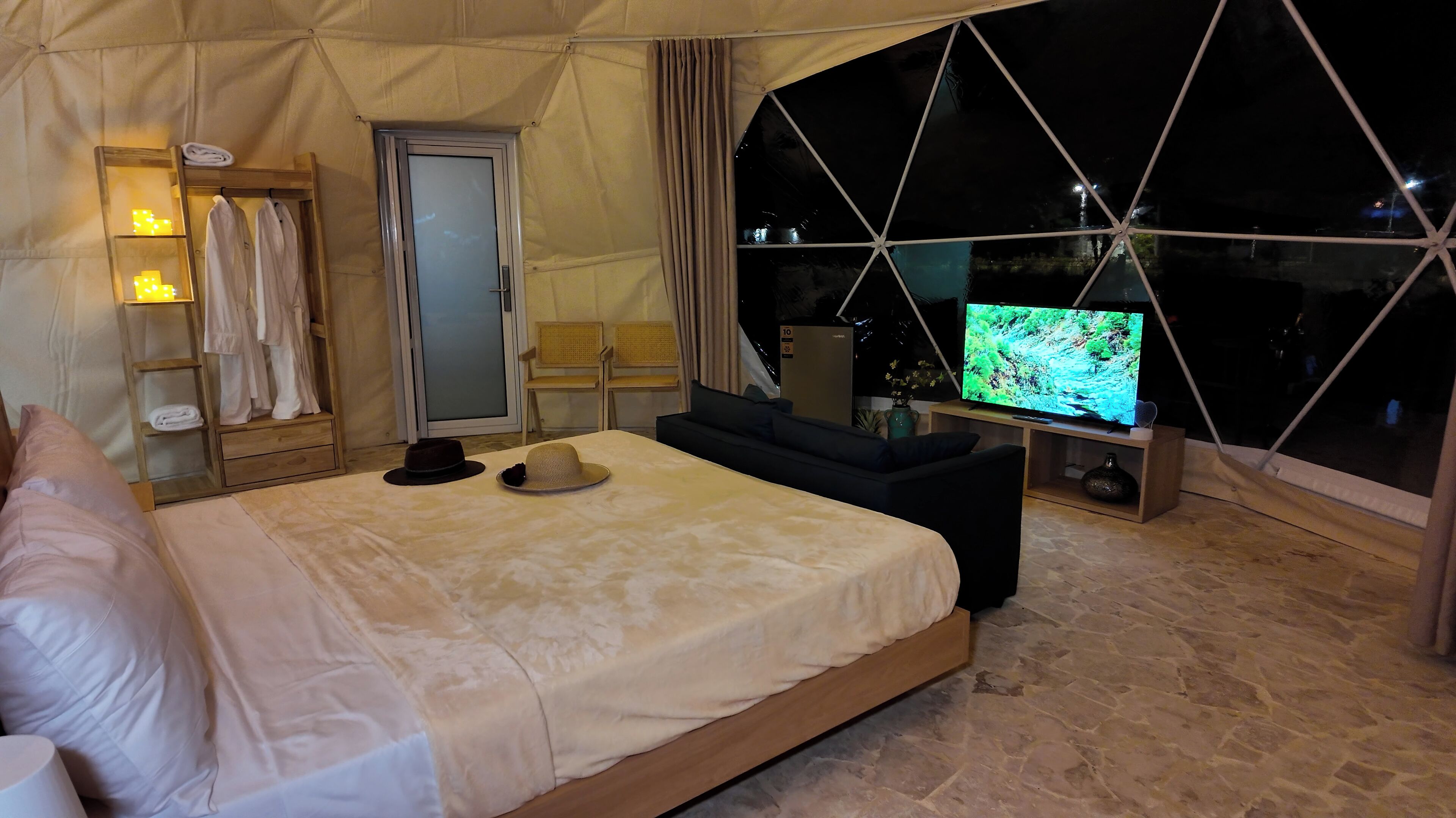 A bedroom with a bed, a TV, a sofa, and a window.