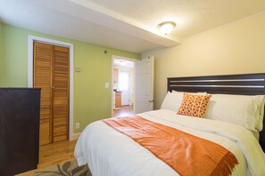 A bedroom with a bed, a wardrobe, and a door leading to a bathroom. - Kendall Square Apartments by Next Star (Cambridge)