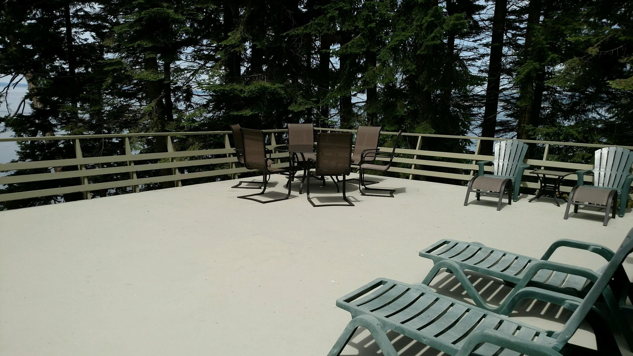 An outdoor seating area with tables and chairs, surrounded by a wooden fence and trees.