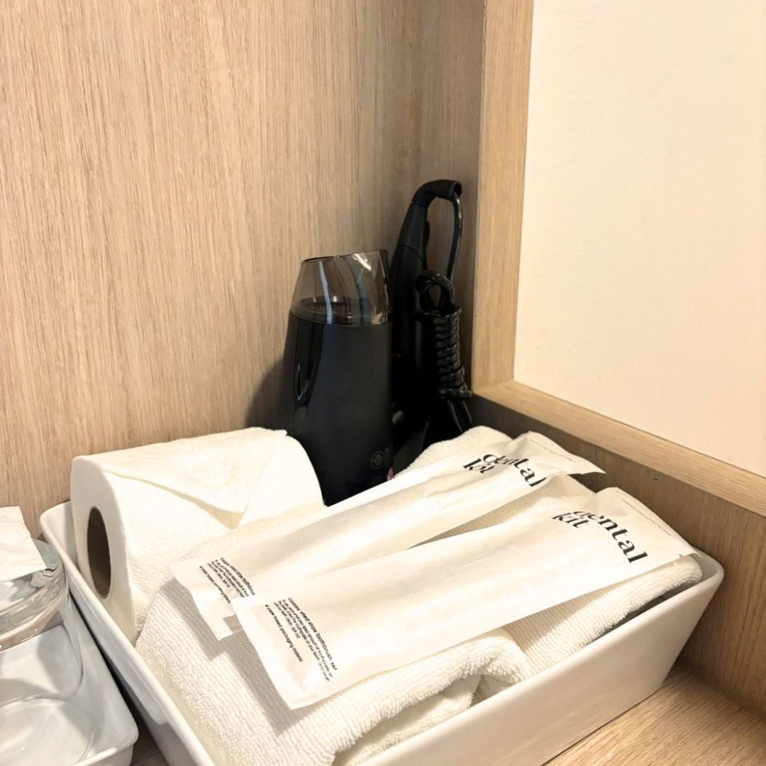 A hotel room with a wooden wall, a black vacuum cleaner, and a white towel with a label.