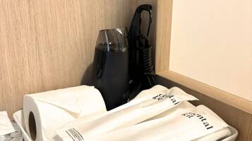 A hotel room with a wooden wall, a black vacuum cleaner, and a white towel with a label.
