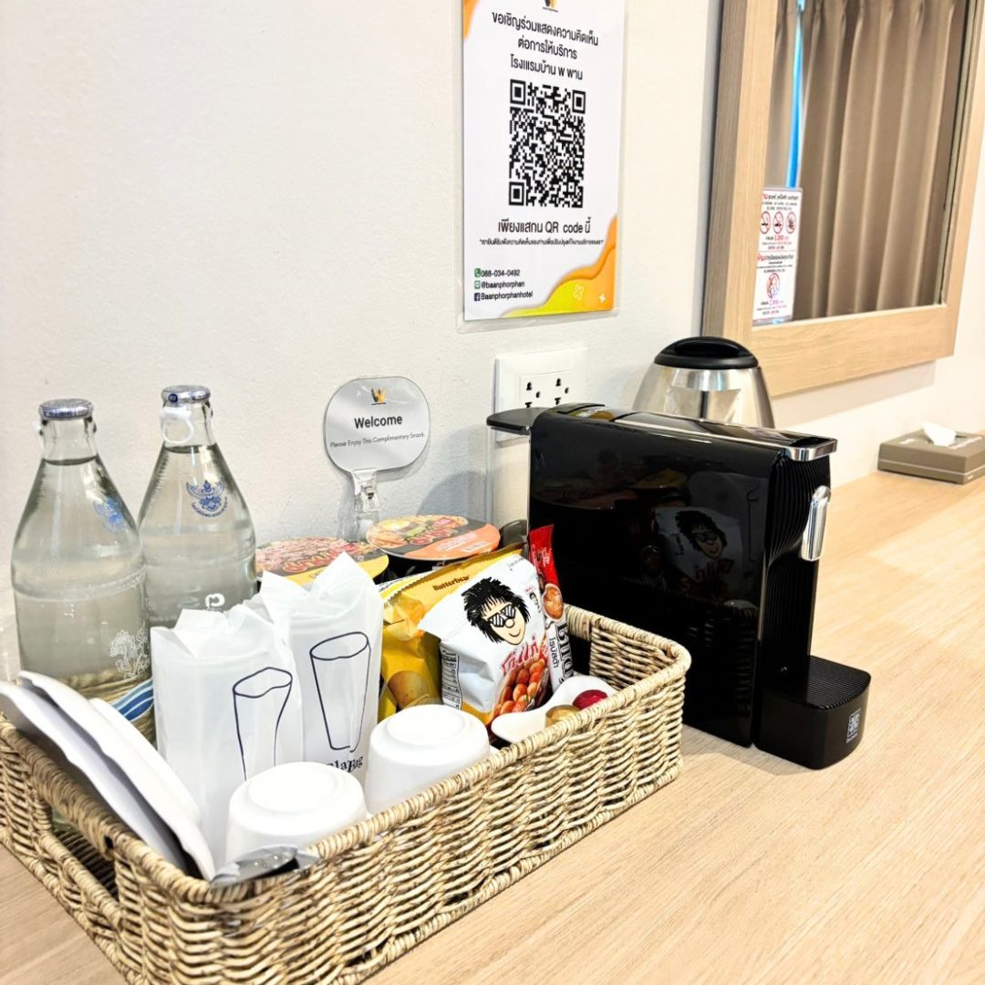 Placa de boas-vindas, código QR, máquina de café e cesta com lanches e bebidas.