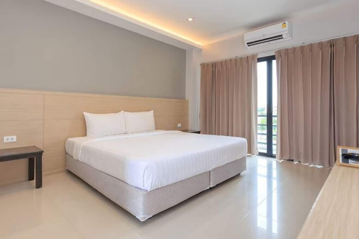Habitación de hotel con una cama grande, una mesita de noche, una ventana con cortinas y un equipo de aire acondicionado.