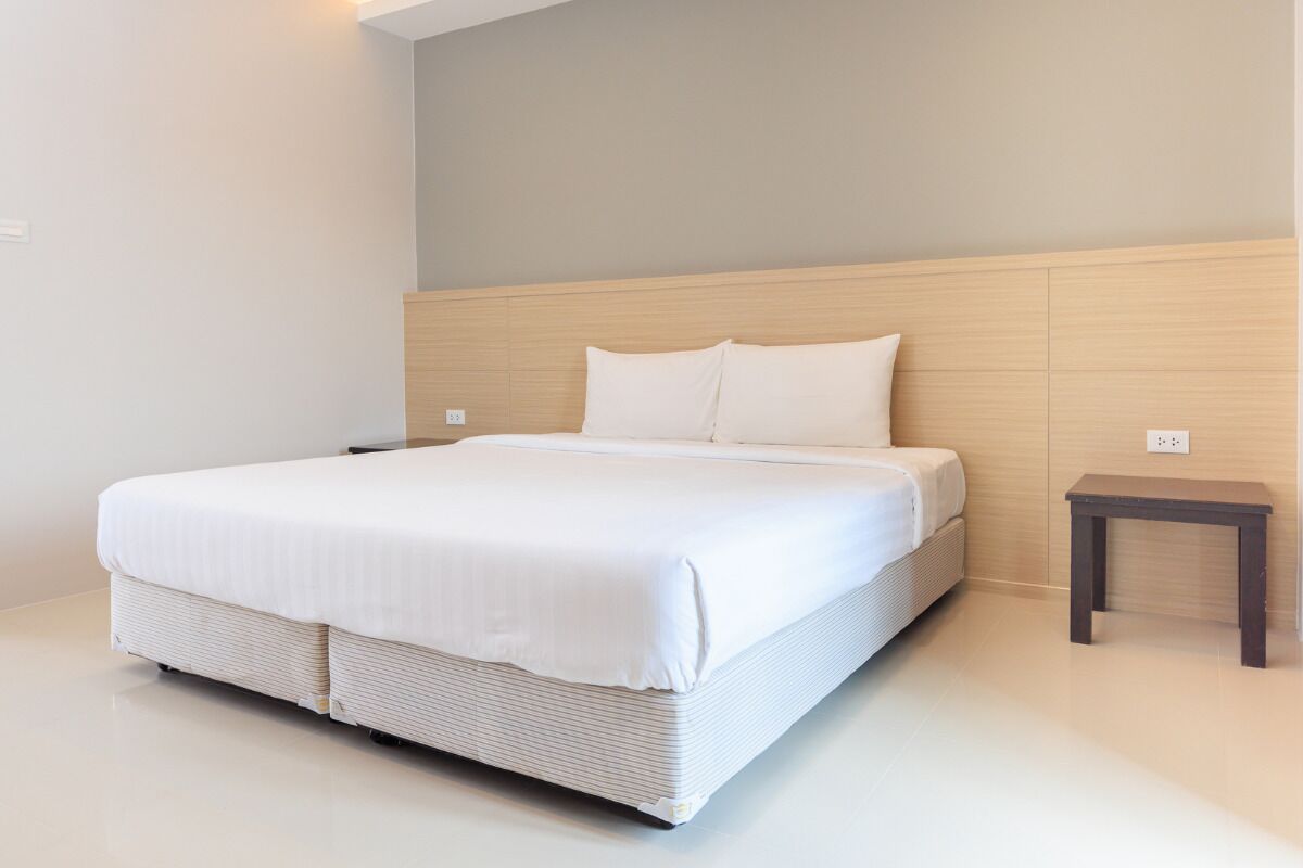 Een moderne slaapkamer met een groot bed, een houten hoofdbord en een klein nachtkastje.