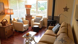 A cozy living room with a sofa, armchairs, a table, and a fireplace. - Mutiny Bay Cottage (Freeland)