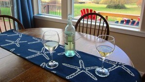 A dining table with a starfish tablecloth, two wine glasses, and a bottle of water. - Mutiny Bay Cottage (Freeland)
