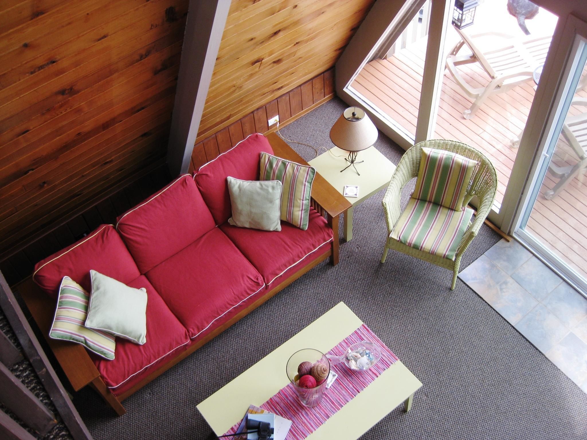 A cozy room with a red sofa, striped armchair, and a small table with a lamp and decorative items.