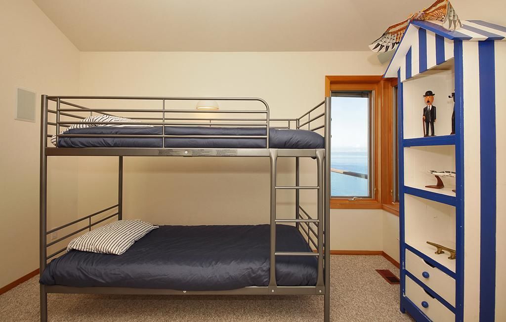 A bunk bed room with a window and a blue and white shelf with figurines.