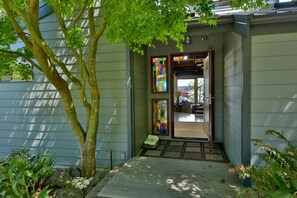 A house with a covered porch, a tree, and a colorful stained glass window.