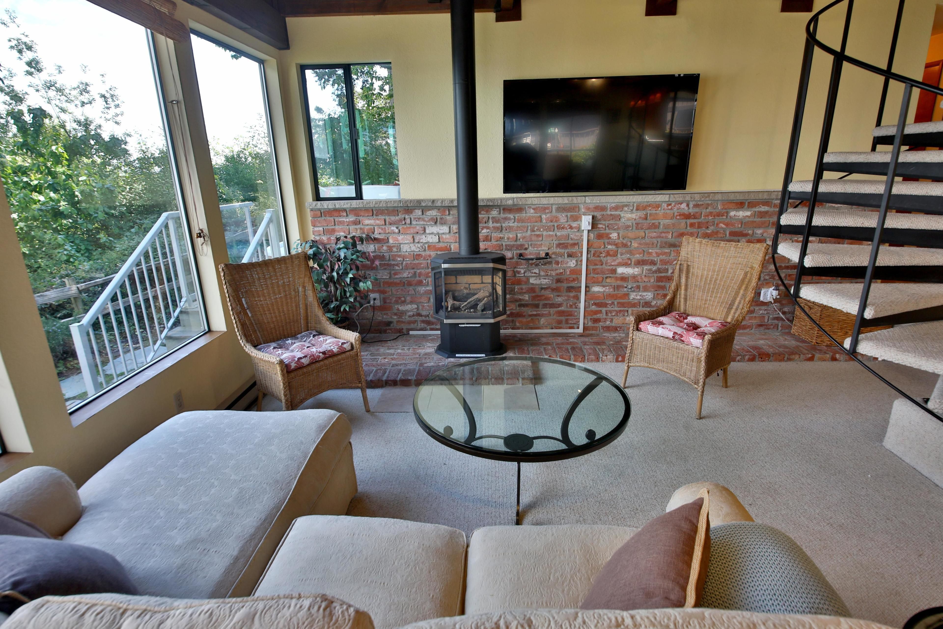 A cozy living room with a fireplace, comfortable seating, and a staircase.