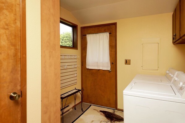 A laundry room with a washing machine, a drying rack, and a door with a window.
