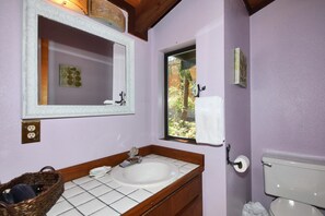A bathroom with a white sink, mirror, and window.