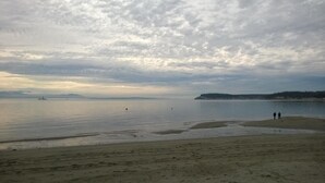 Una playa con un mar tranquilo, una costa lejana y un cielo nublado.