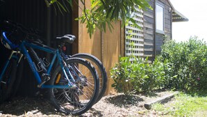 A blue bicycle parked near a wooden fence with a small garden area. - Herb Cottage (Haumoana)