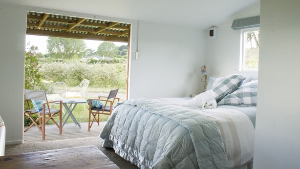 A bedroom with a bed, a window, and a view of the outdoors. - Herb Cottage (Haumoana)