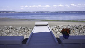 Una terraza de madera que da a una playa con costa rocosa y una vista despejada del océano.