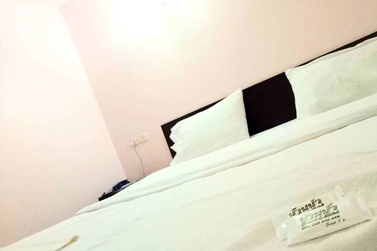 Ein Hotelzimmer mit einem Bett, einem schwarzen Kopfteil und einer weißen Wand.